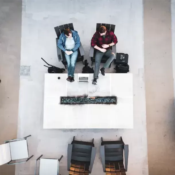 兩個人坐在火爐旁邊看著筆電螢幕聊天